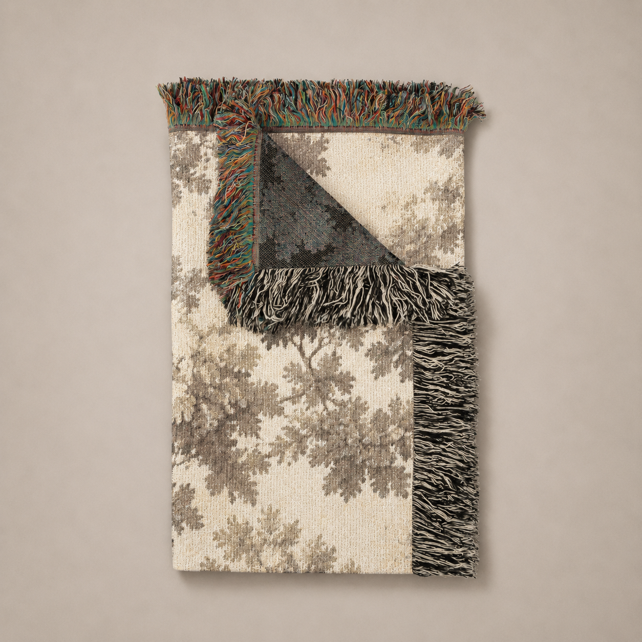 Decorative woven blanket with a tree pattern and fringed edge on a beige background