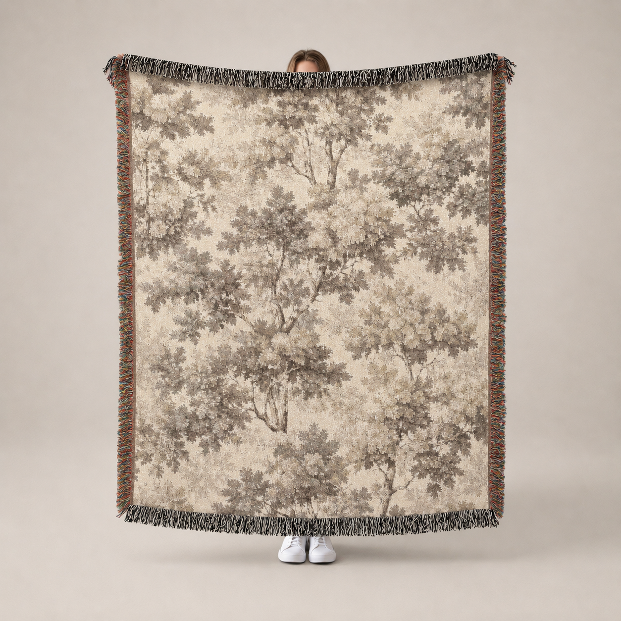 Person holding a large tree-patterned blanket with a neutral background